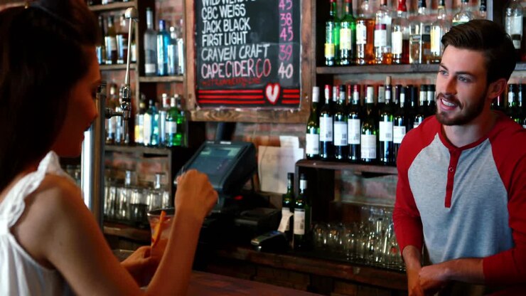 barman che interagisce con il cliente femminile mentre serve un cocktail