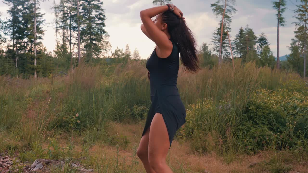 En attraktiv dame, der udfører en rytmisk dans i naturen på en solrig dag - Medium skud