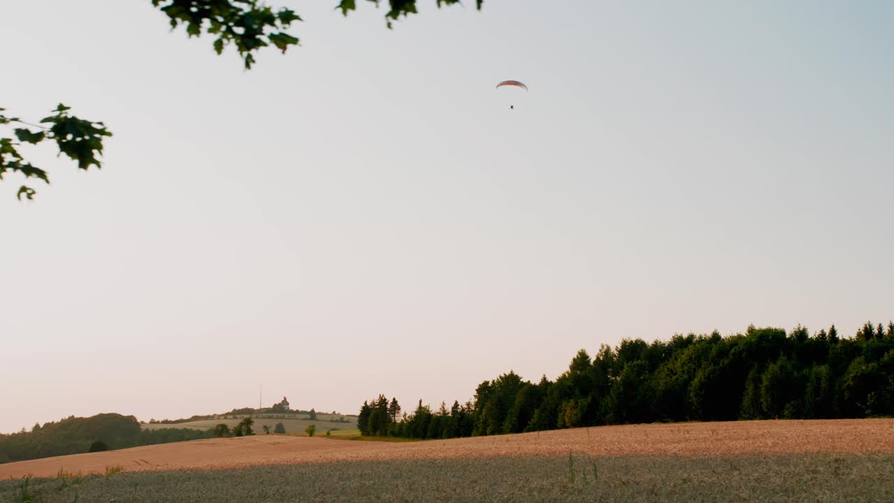 parapente en solitario sobre amplios y tranquilos campos amarillos y bosques, panorámica