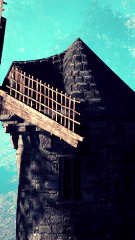 a stone windmill with a wooden blade stands against a blue sky