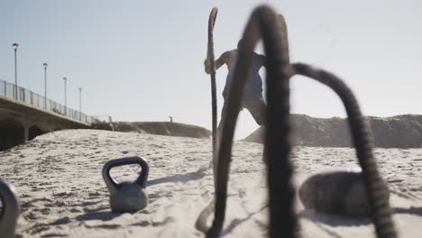 hombre afroamericano enfocado haciendo ejercicio con cuerdas de lucha al aire libre en la playa