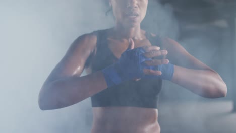 african american woman tightening boxing hand wraps in an empty urban building