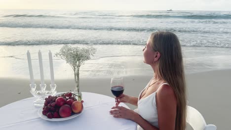 Woman Enjoy the Quiet and Peaceful Atmosphere on the Ocean Shore with Fine Wine and Fresh Fruit Woman Enjoy the Quiet and Peaceful Atmosphere on the Ocean Shore with Fine Wine and Fresh Fruit