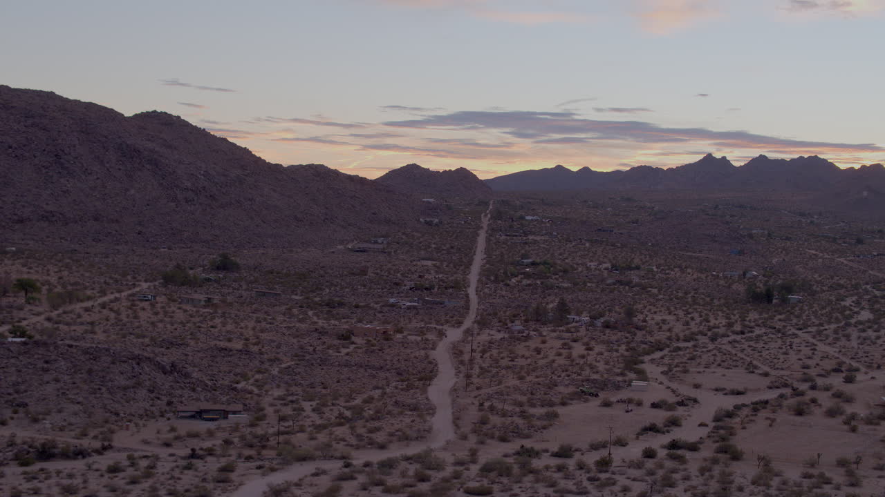 antena del paisaje desértico en joshua tree, california al atardecer con un camino de tierra solitario que va directamente hacia atrás y hacia las colinas