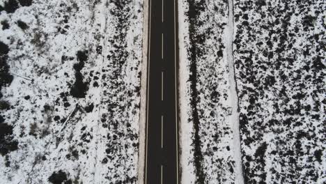 Lange,-Leere-Straße-Aus-Der-Vogelperspektive,-Die-Entlang-Der-Schneebedeckten-Hochlandlandschaft-Umkehrt