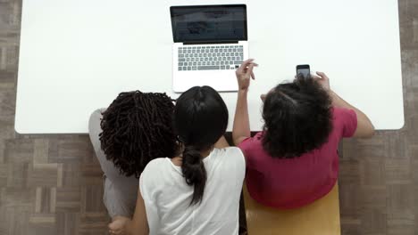 Top-view-of-women-working-with-laptop-while-sitting-at-table