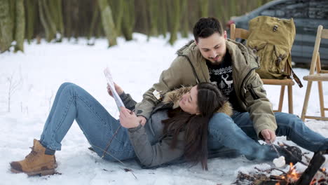 pareja caucásica acampando en un bosque nevado.