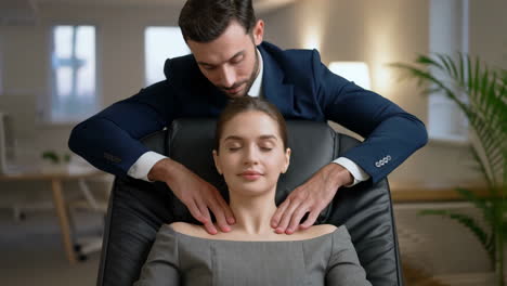 woman receives a neck and shoulder massage from a man in an office