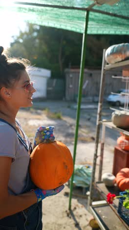 mujer sosteniendo una calabaza en un mercado al aire libre