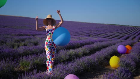 woman in a multicolored suit with circles and a hat holds large inflatable