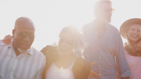 portrait of mature friends walking along path through campsite at sunset