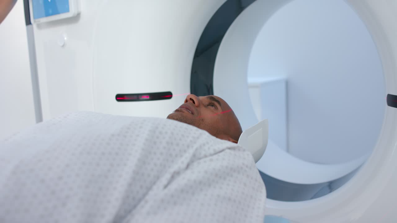 Lo scanner sta avviando la scansione, il lettino sta facendo scorrere il paziente nella gantry mentre il laser sta allineando la guancia