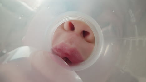 toothless girl drinks water from bottle neck in small sips