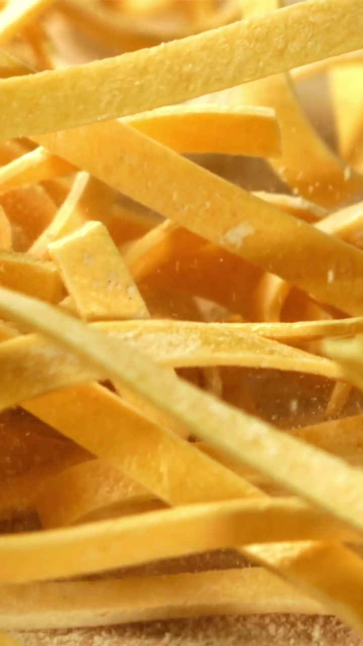 Fresh Tagliatelle Pasta Falling onto a Floured Surface in Slow Motion
