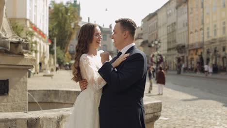 newlyweds, caucasian groom with bride standing, embracing, hugs on city street, wedding couple