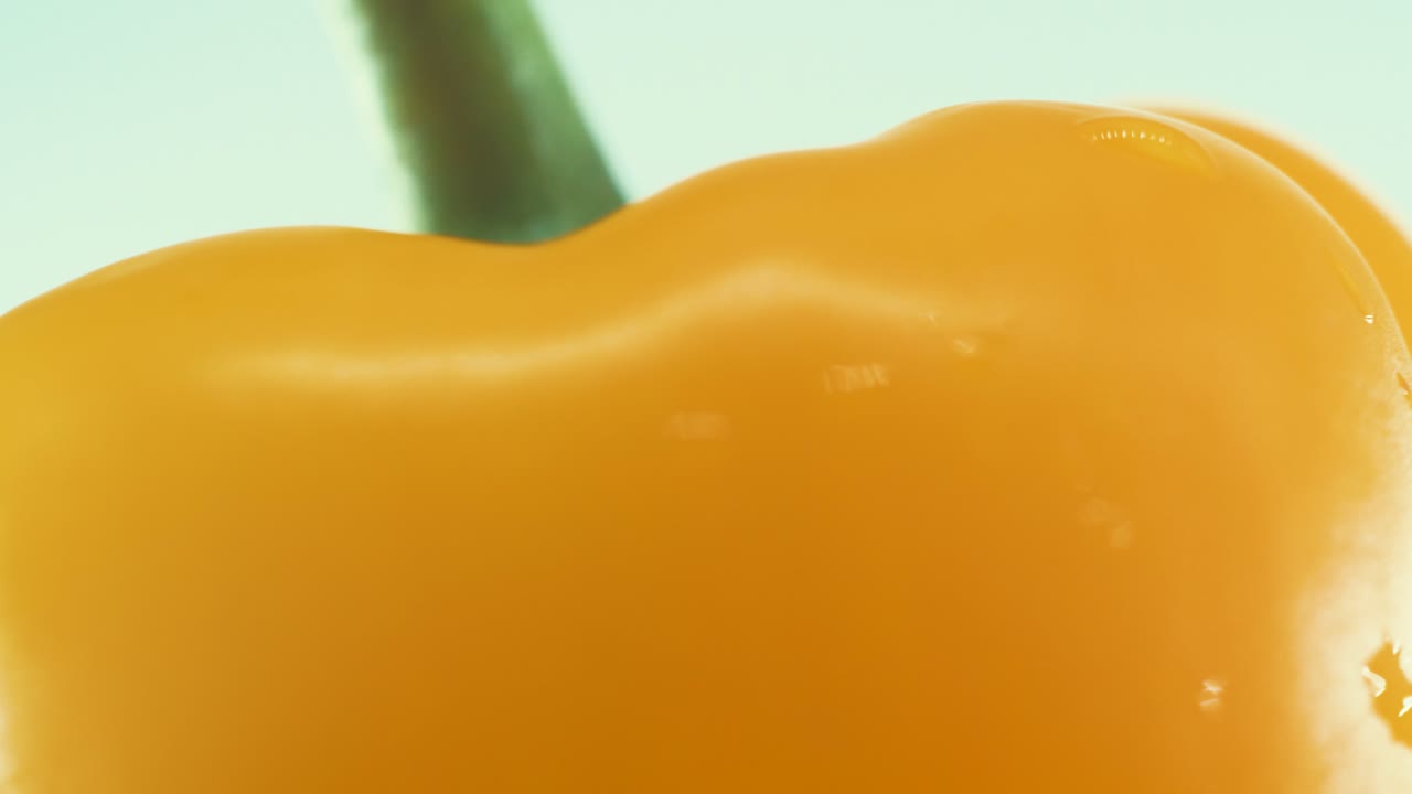 Una ripresa macro ravvicinata di un peperone giallo dolce, bagnato e lucido, su un piedistallo rotante a 360 gradi, slow motion, 4k