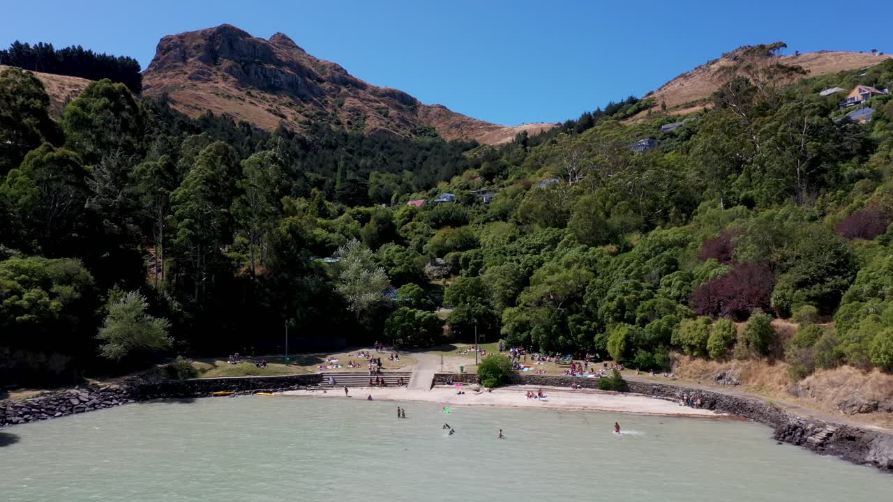 Flyover sea and beach to reveal car park and houses on hill beyond