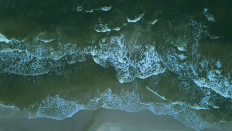 Top-down-View-Of-A-Blue-Waves-Washing-Up-On-The-Sandy-Shore-Of-Plaza-Karwia-Beach-In-Summer-Near-The-Seaside-Village-Of-Karwia-In-Poland