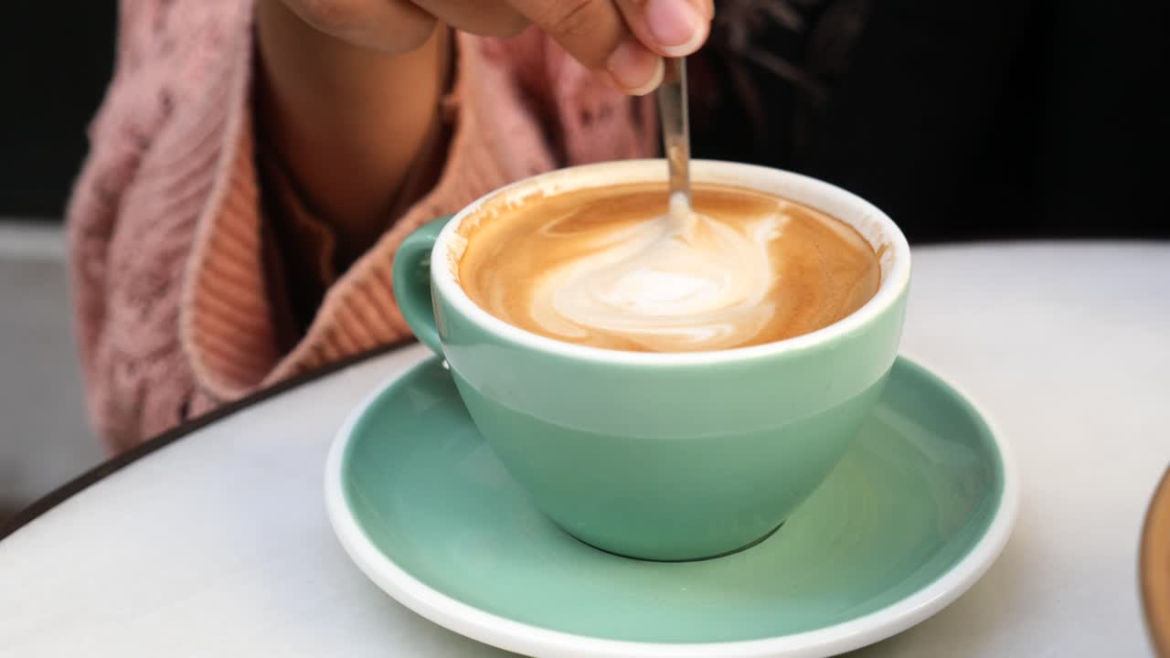 Woman stirring a cup of coffee at a cafe