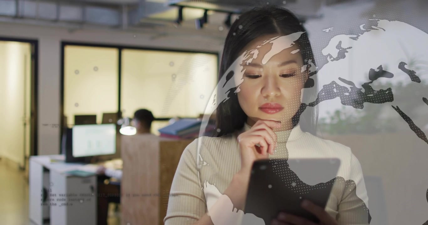 ビジネスオフィスで、中国人女性がタブレット画面をタップして世界地図のオーバーレイを起動し、データをレビューしている。