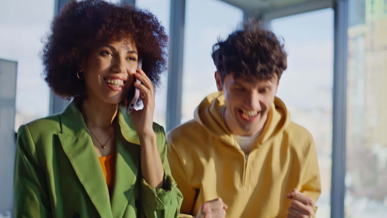 Company employees speaking cellphone getting good news in light office closeup