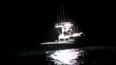 a boat sits in the water at night while a man works on the deck