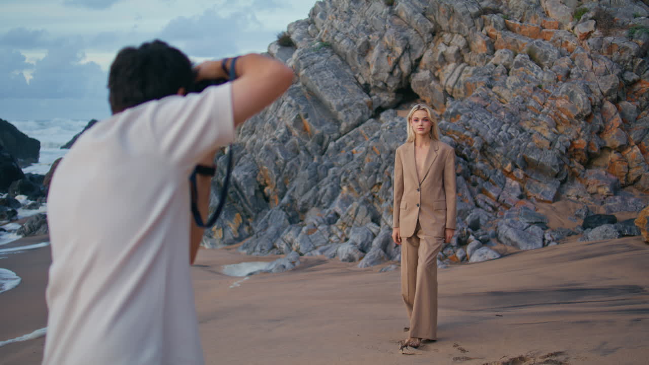 바다 해변에서 패션 세션에서 모델링하는 소녀. 매력적인 금발 소녀가 슈트에 포즈를 취하고 있습니다.