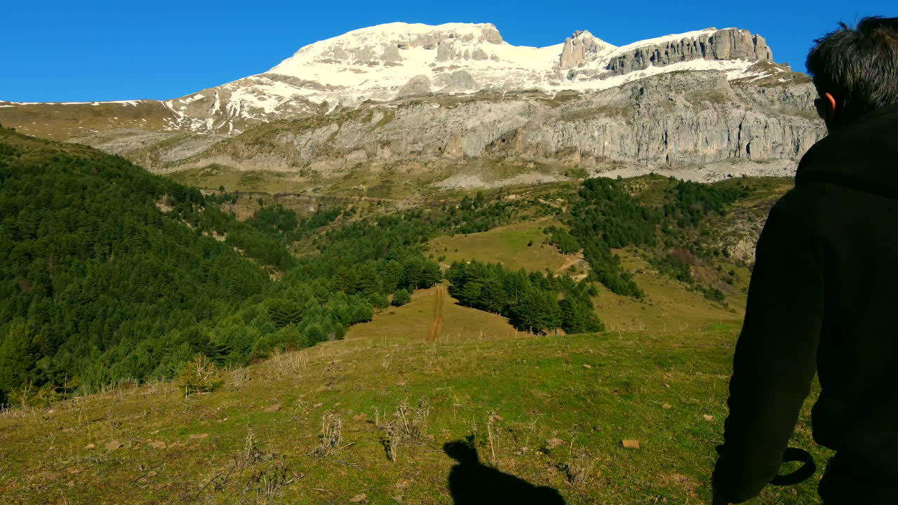 siguiendo a un hombre haciendo senderismo en las montañas españolas cuando ve un refugio de montaña