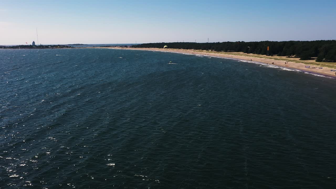 Aerial view of people parasailing, at a beach, warm, windy, summer day, in Scandinavia - reverse, drone shot