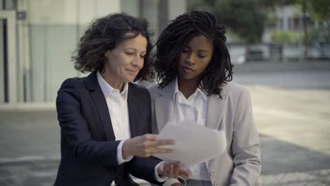 Front-view-of-confident-colleagues-discussing-documents-on-street