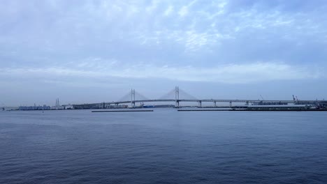 overcast skies over calm waters with a distant suspension bridge, serene scene