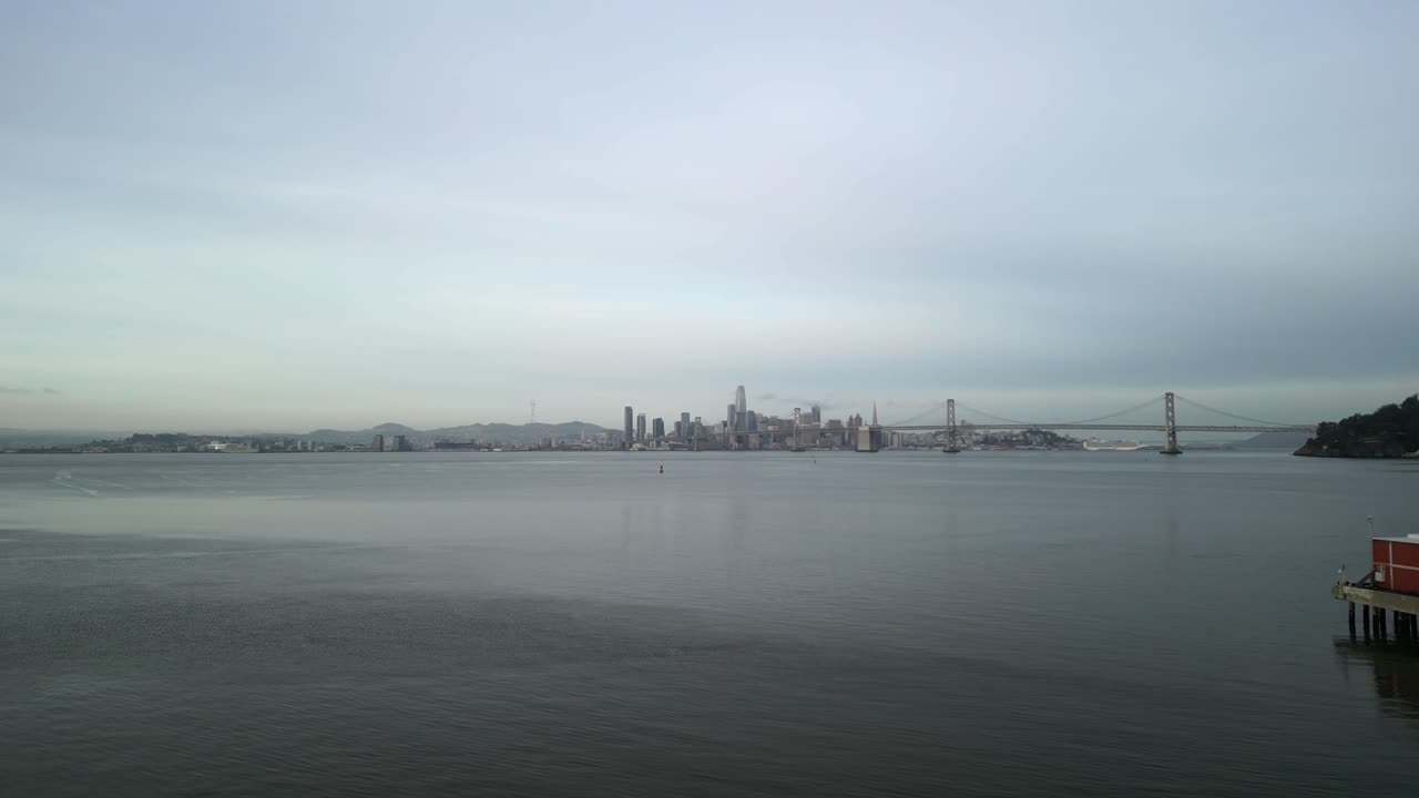 A drone soars above the Bay Bridge, revealing the intricate network of roads and shipping activity below.