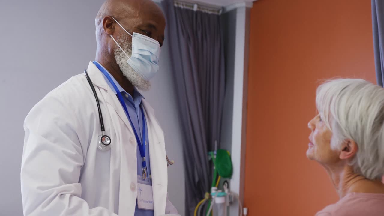 病院で高齢の白人女性患者の首を検査しているアフリカ系アメリカ人の男性医師