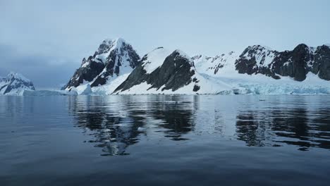 Soleadas-Montañas-Invernales-De-La-Antártida-En-La-Costa,-Paisaje-Costero-En-La-Península-Antártica,-Océano-Austral-Plano-Y-Tranquilo-Agua-De-Mar-Del-Océano,-Paisaje-Marino-De-Montaña-En-Una-Hermosa-Escena-Dramática