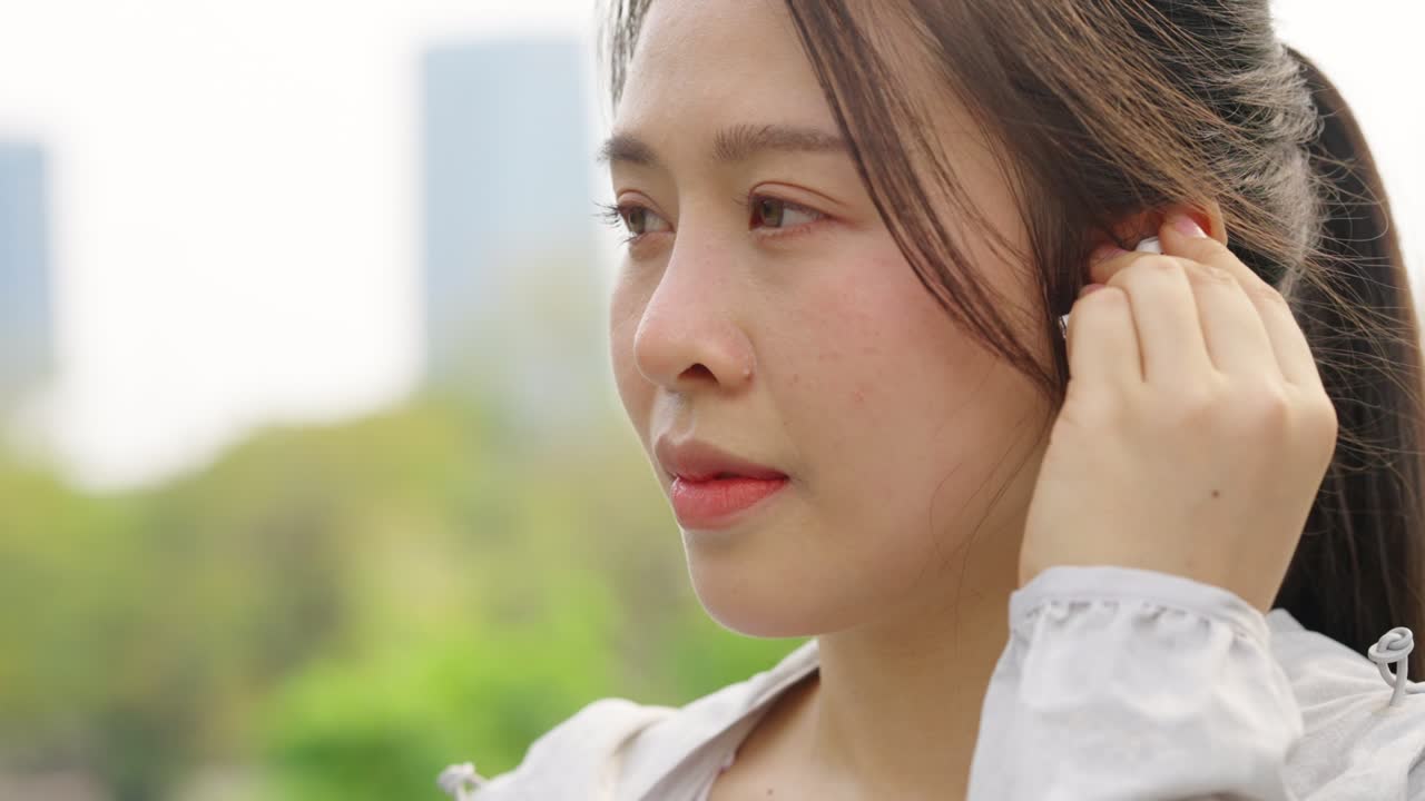 4k 아시아 여성이 아침에 공원에서 조하는 동안 음악을 듣고 있습니다.