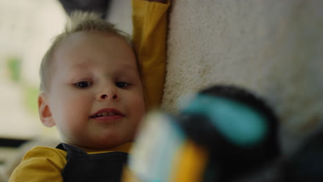 retrato de un niño lindo acostado en la alfombra en el interior. niño gracioso jugando con un coche de juguete en el interior.