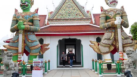 visitors explore wat arun's iconic entrance statues