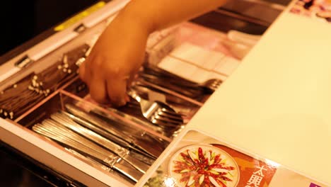 hand arranging cutlery in a drawer