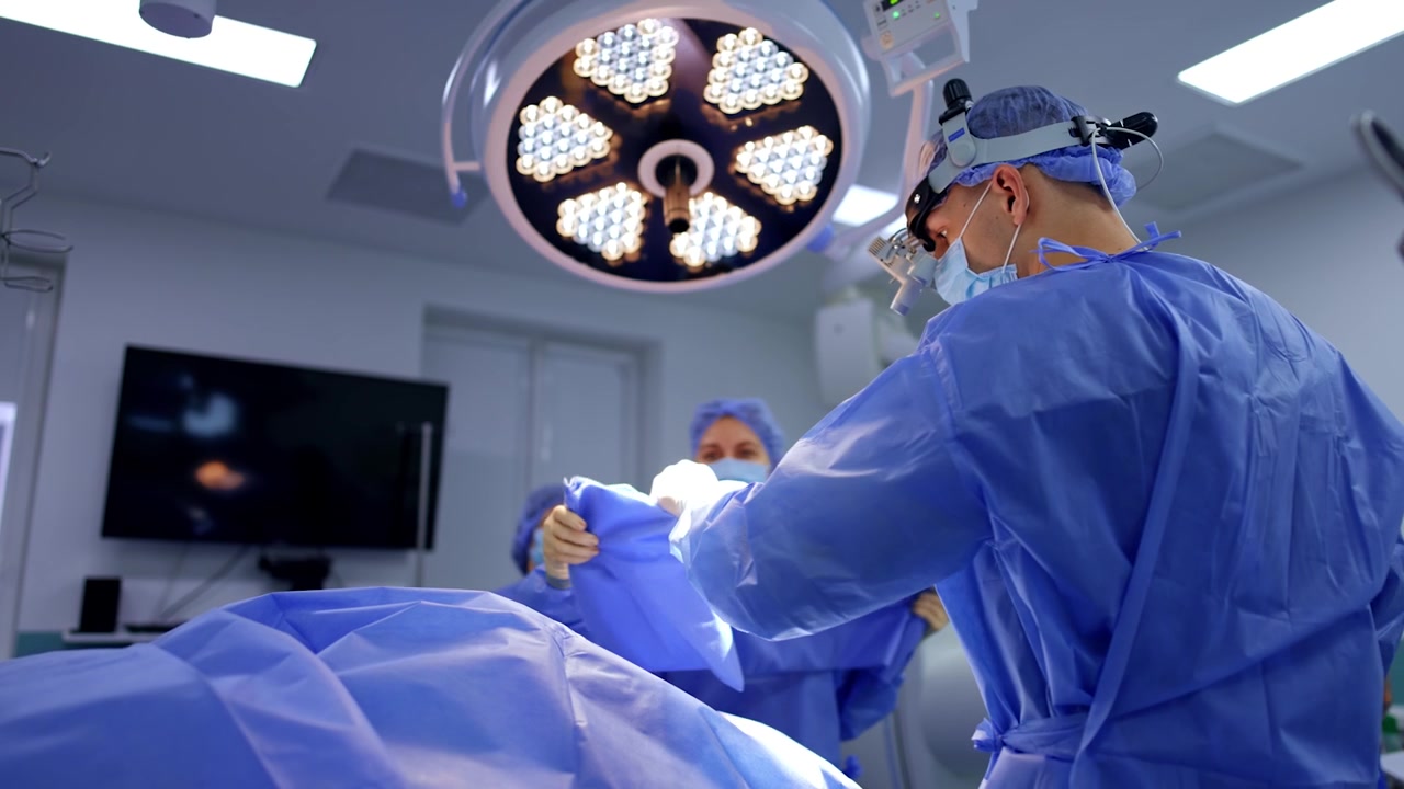 I medici prendono un telo blu da stendere sul paziente. Il personale medico si sta preparando per l'operazione.