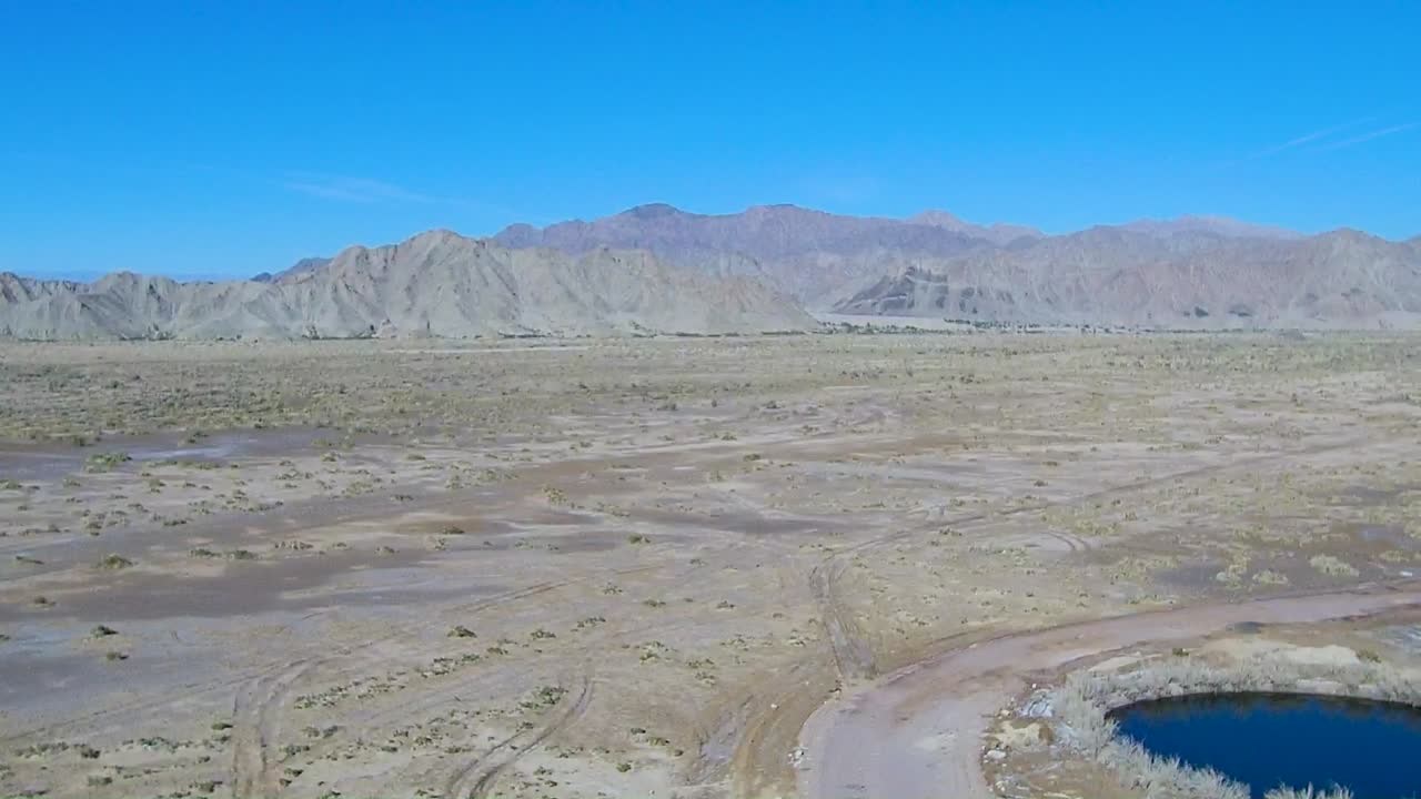 vista de un dron que desciende sobre una llanura que muestra una montaña al fondo y un río a un lado