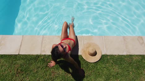 mixed race woman sitting at the poolside sunbathing