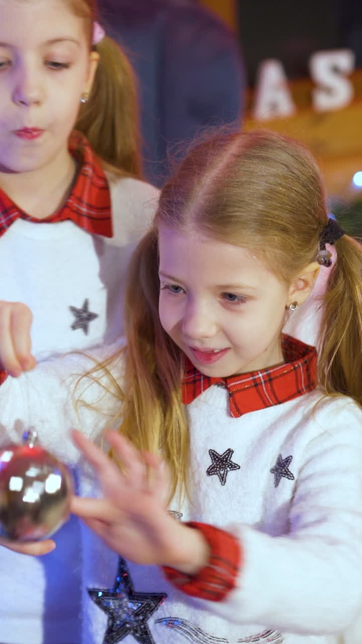 Happy little girls sisters decorating christmas tree with balls. children decorating a Christmas tree. Vertical video