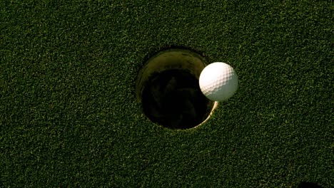 golf ball rolling into the hole on putting green