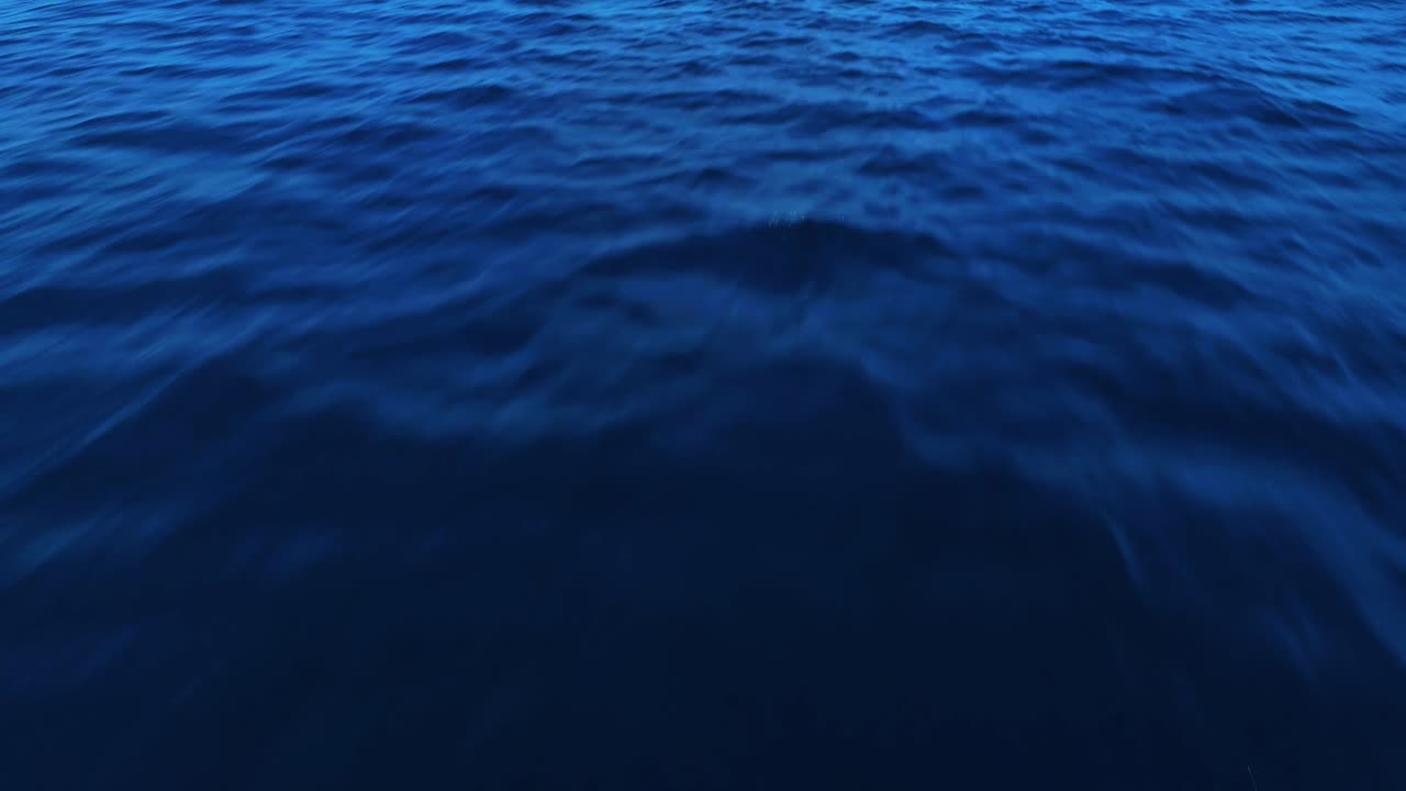 Low aerial dolly above deep blue ocean texture ripples of caribbean sea