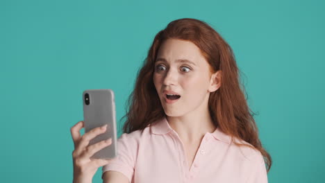 redheaded girl in front of camera on turquoise background.