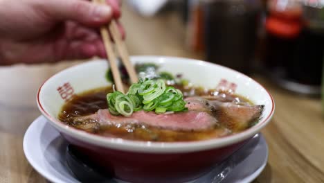 person eating ramen with chopsticks in a restaurant