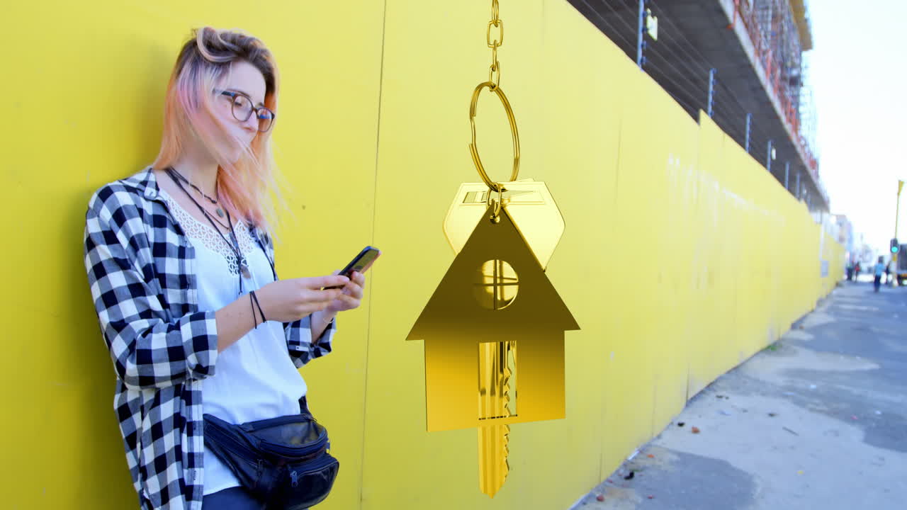 Animation of hanging golden house keys over caucasian woman using smartphone on the street