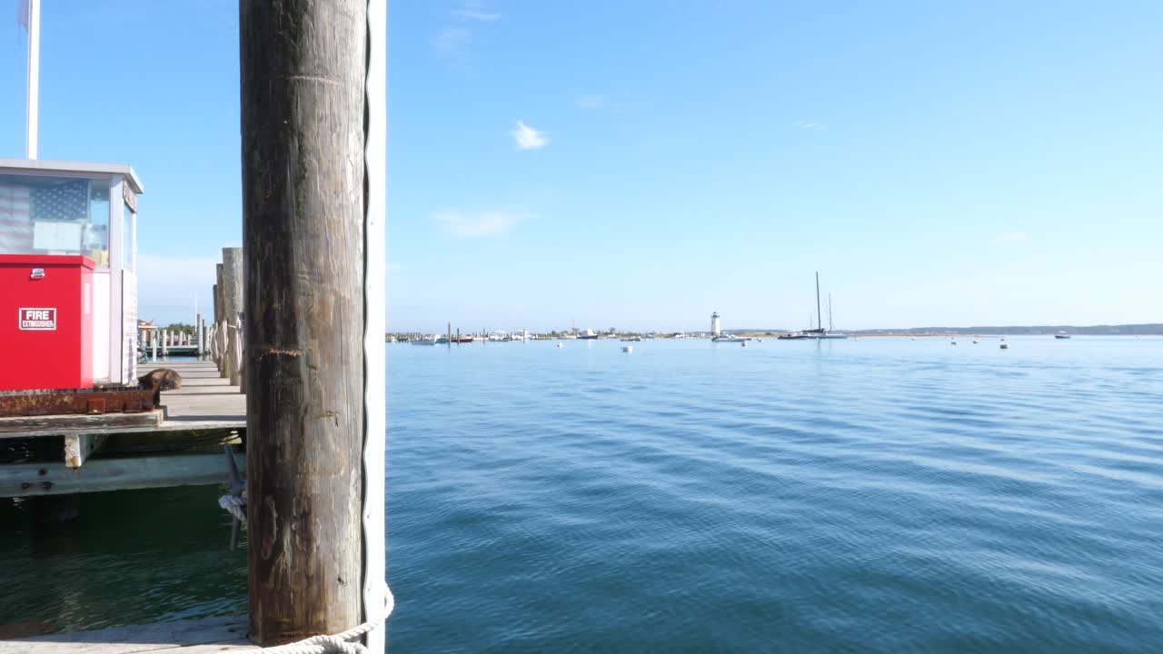 Ruhiges Meer mit Pier, Booten und Leuchtturm an einem sonnigen Tag
