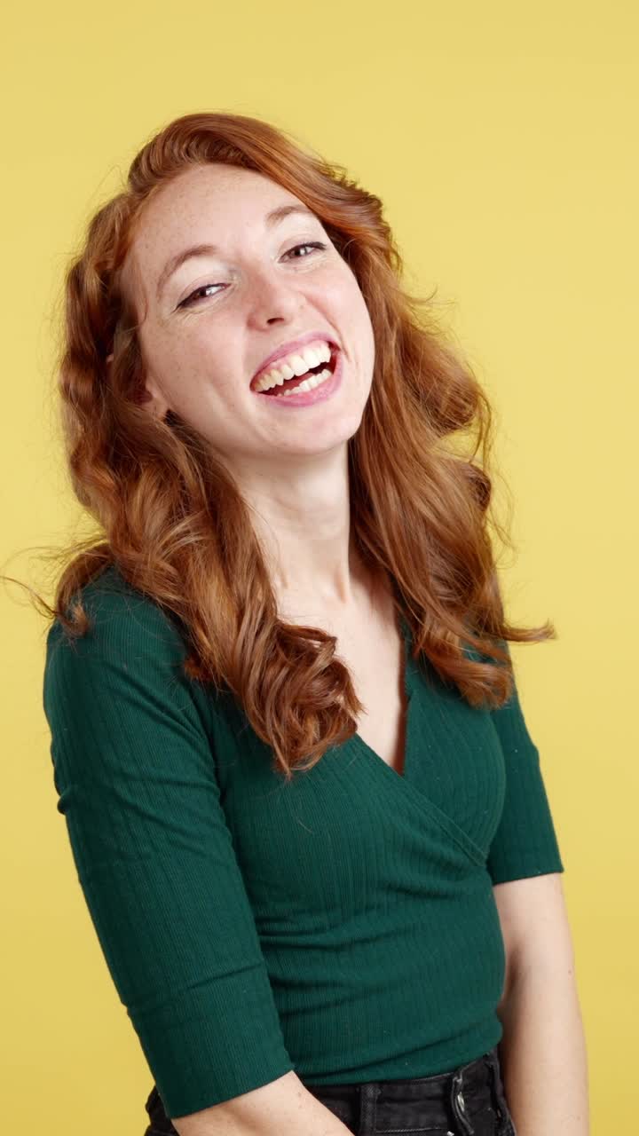 Joyful Red-Haired Woman Laughing on Yellow Background