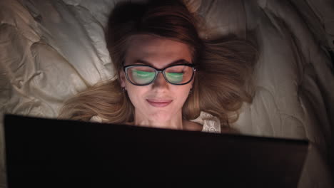 mujer trabajando en la computadora portátil en la cama por la noche